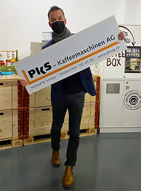 Christian Panzeri mit Schild der PKS Kaffeemaschinen AG in den Händen